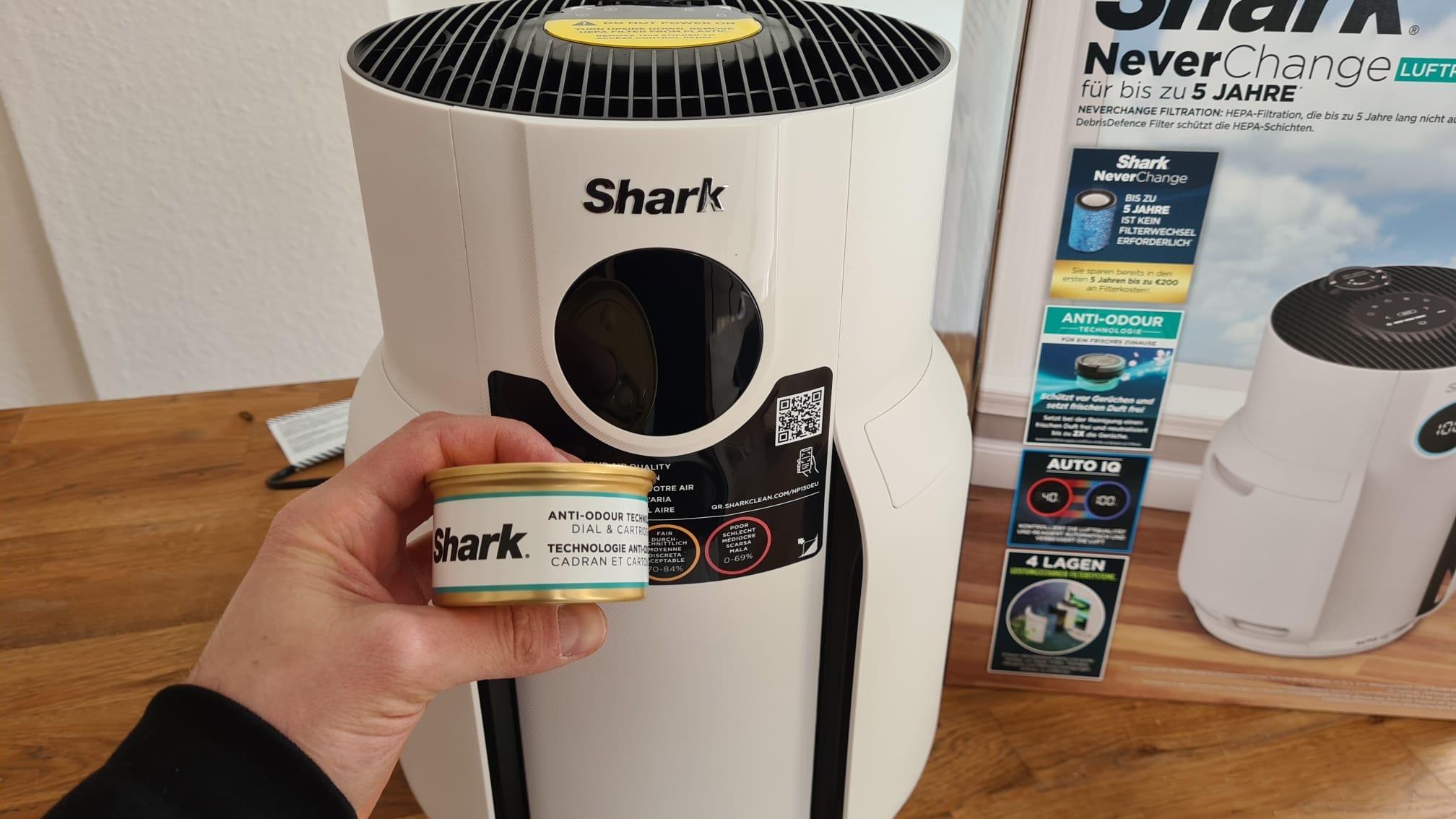 Die Anti-Geruch Kassette des Shark HP300EU Luftreinigers wird vor dem Gerät in der Hand gehalten und präsentiert.